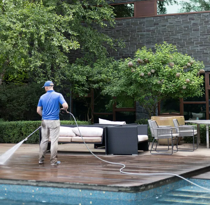 A Man Pressure Washes the Deck of a Canfield Home Next to the Pool.