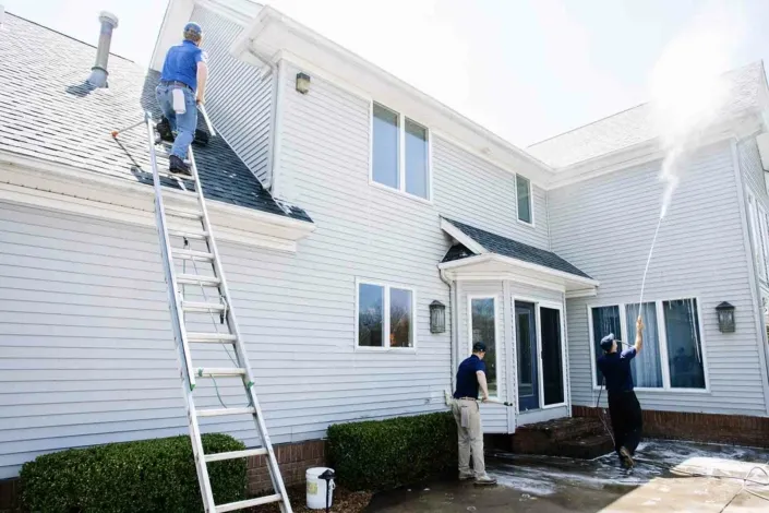 Three Men in Blue Polos Clean a Two Story, White Home in Canfield.