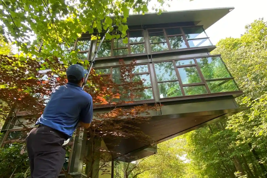A Man in a Blue Polo Cleans a Riverfront Home's Windows in Poland, Ohio.