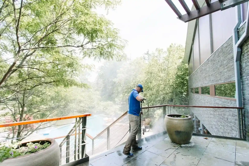 A Man in a Blue Polo Pressure Washes a Deck in Mahoning Valley.