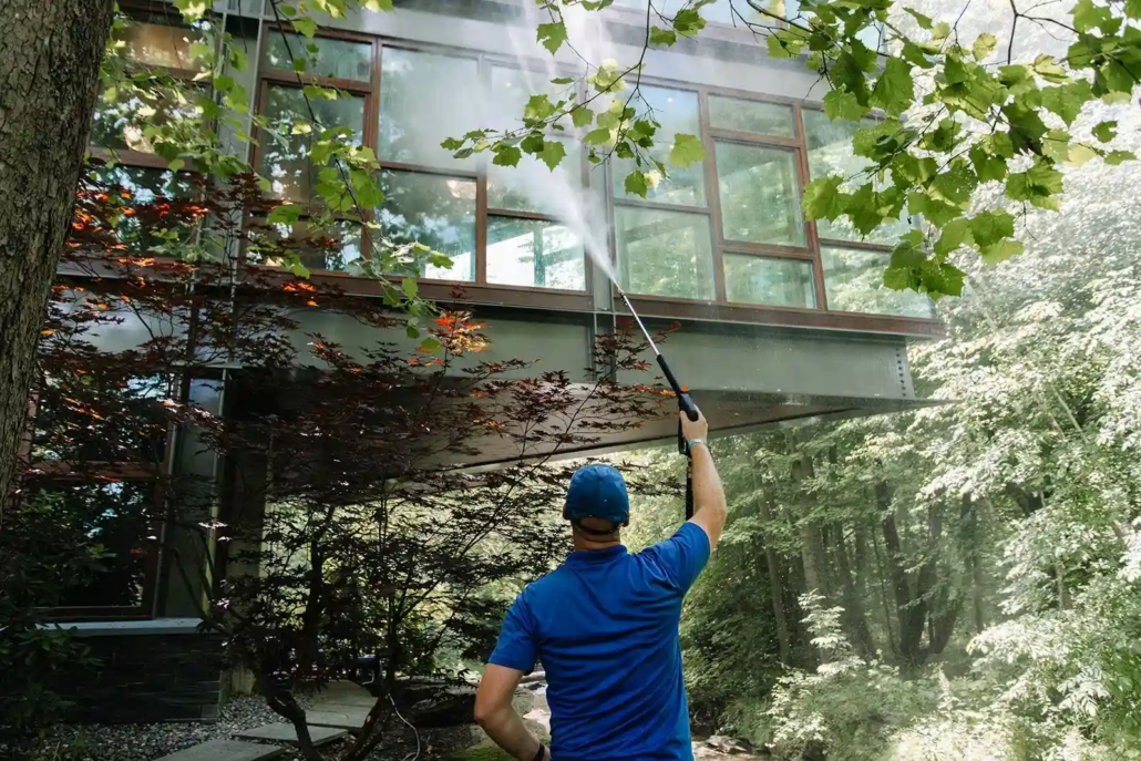 A Window Cleaner in a Blue Polo Cleans a Riverfront Home's Windows.