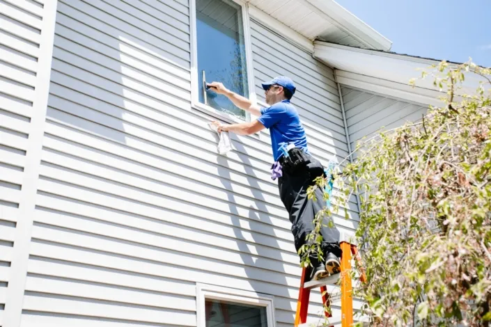 A Man Squeegees the Windows of a Two Story White Home in Canfield.