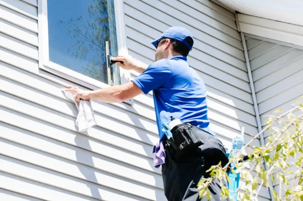 A P&D Power Washing Employee Cleans Windows of a Two Story Home in Mahoning Valley with White Siding.