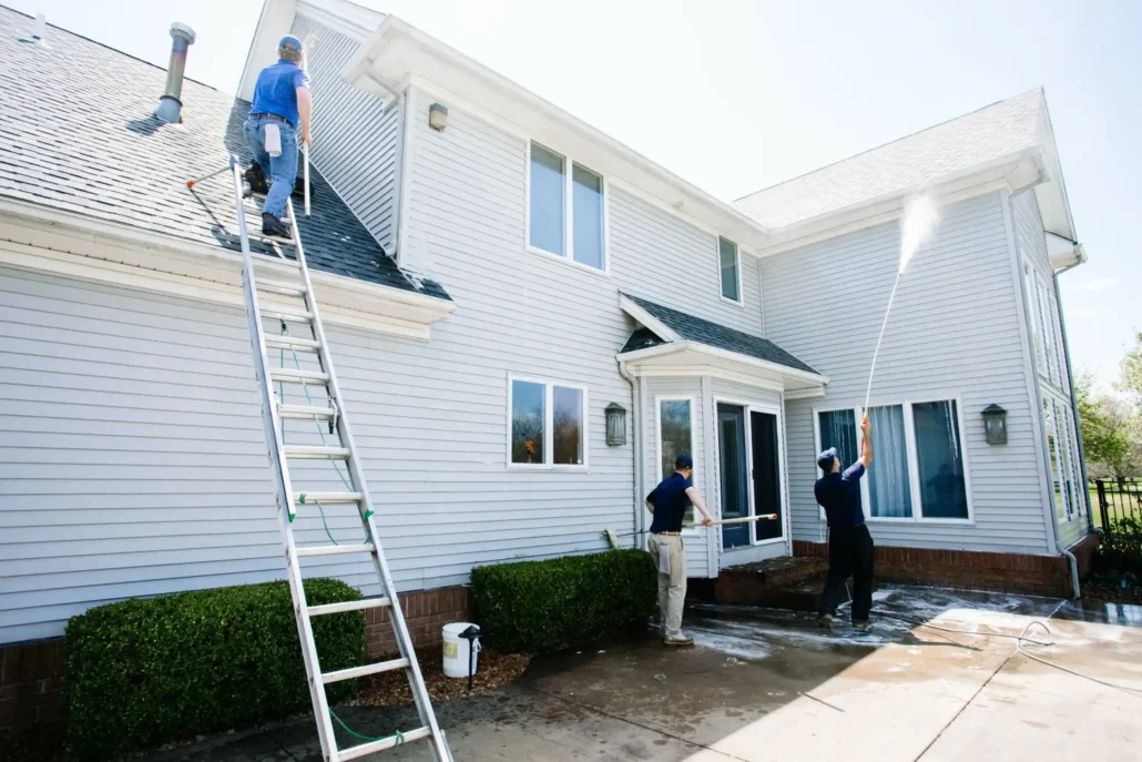 Three P & D Power Washing Employees Clean the Roof, Windows, and Siding on a White, Two-Story Suburban Home.